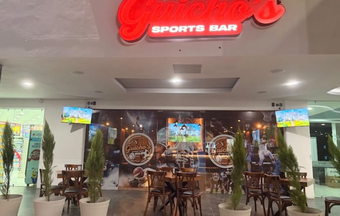 Entrance to Guicho's Sports Bar in Nuevo Vallarta with its red neon sign and outdoor plaza seating